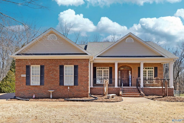 view of front facade featuring brick siding, a porch, and roof with shingles