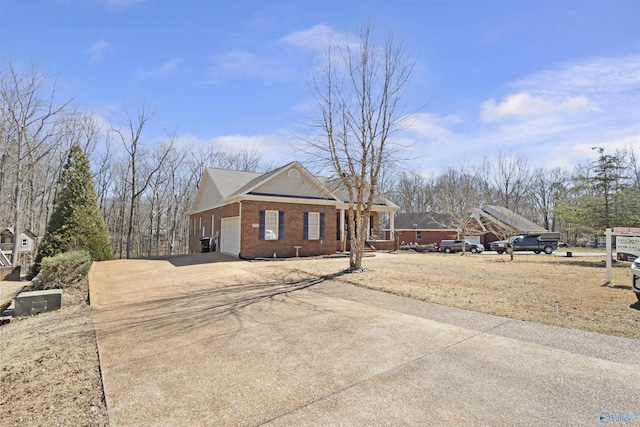 view of side of home featuring an attached garage, brick siding, and driveway