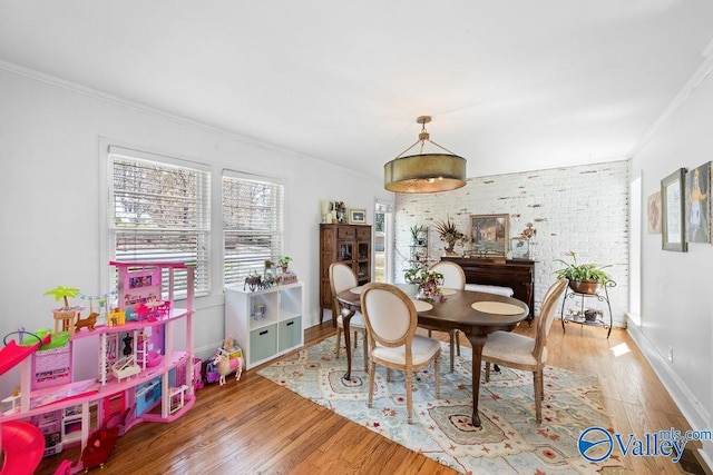 dining area featuring wood finished floors, baseboards, brick wall, and ornamental molding