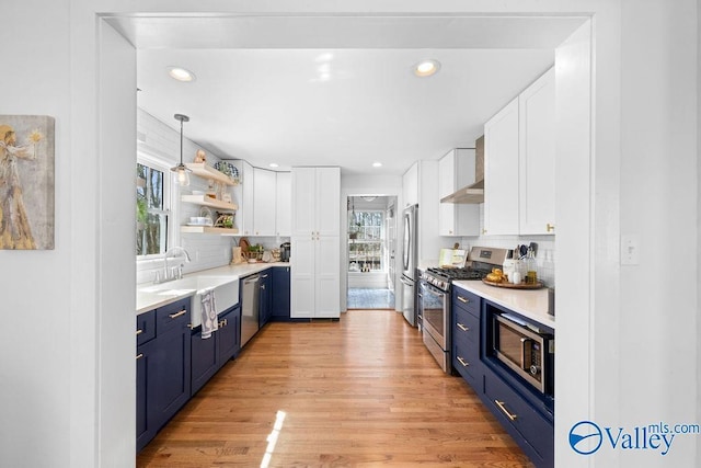 kitchen with backsplash, appliances with stainless steel finishes, light wood-style floors, white cabinetry, and blue cabinets