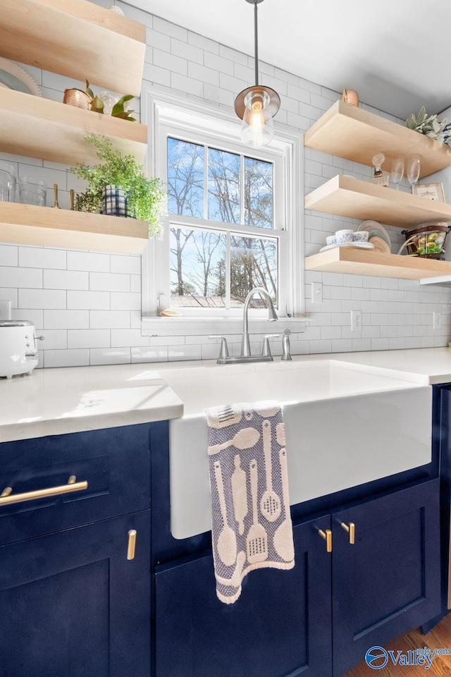 kitchen featuring tasteful backsplash, light countertops, blue cabinets, and open shelves