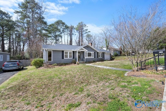 single story home with aphalt driveway, a chimney, a front lawn, and fence