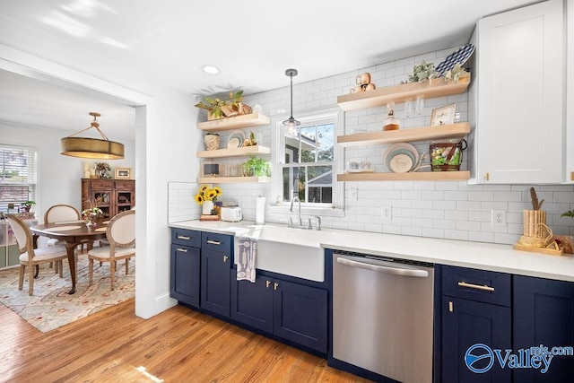 kitchen featuring blue cabinets, open shelves, dishwasher, and a sink