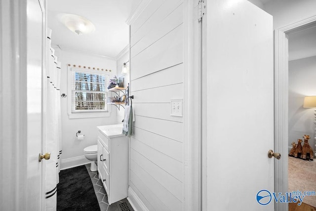 bathroom featuring toilet, vanity, crown molding, and baseboards