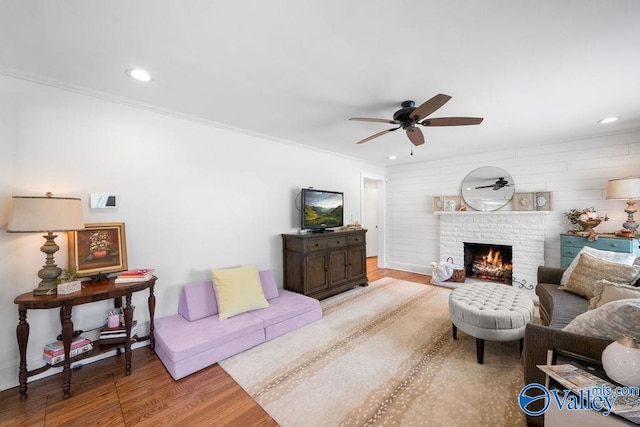 living area with a brick fireplace, recessed lighting, wood finished floors, and ceiling fan