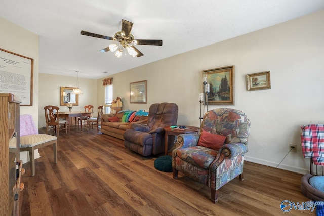 living room featuring dark wood-type flooring and ceiling fan