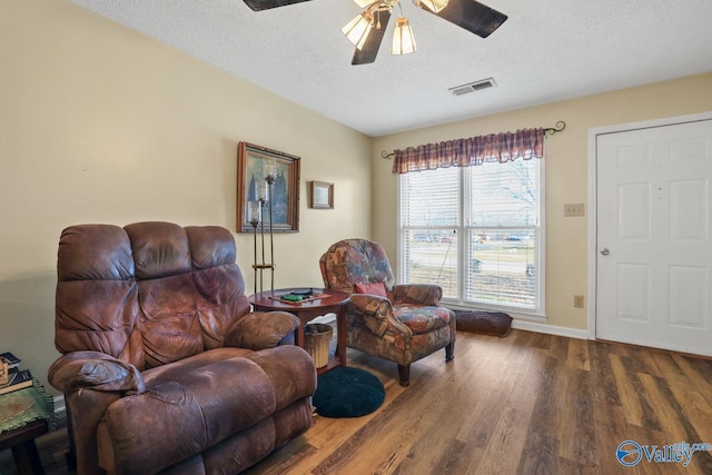 living area featuring hardwood / wood-style flooring, a textured ceiling, and ceiling fan