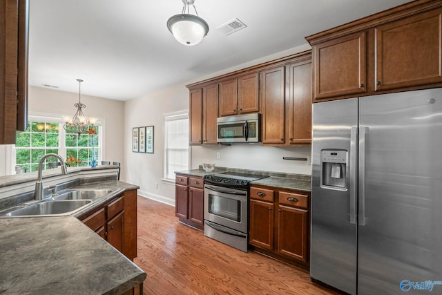 117 Somerset Park Dr NE, Huntsville, AL 35811 - kitchen featuring appliances with stainless steel finishes, a sink, dark countertops, wood finished floors, and decorative light fixtures