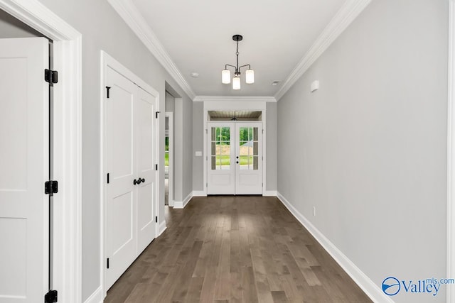 doorway with hardwood / wood-style flooring, crown molding, and a notable chandelier