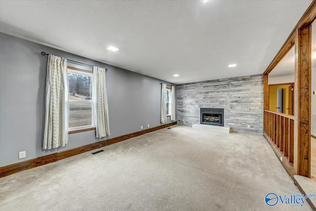 unfurnished living room featuring a tiled fireplace, carpet floors, and wood walls