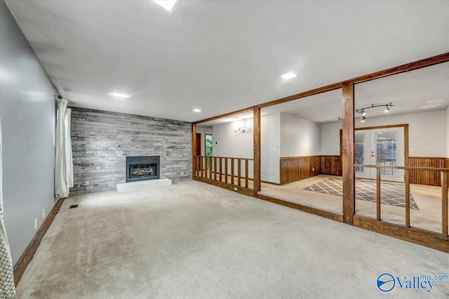 unfurnished living room with light colored carpet, wooden walls, and a tile fireplace