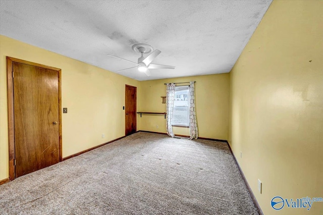 carpeted empty room featuring ceiling fan and a textured ceiling