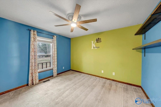 spare room featuring ceiling fan, light carpet, and a textured ceiling