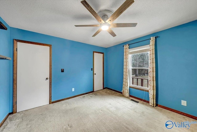 unfurnished room featuring ceiling fan, light colored carpet, and a textured ceiling