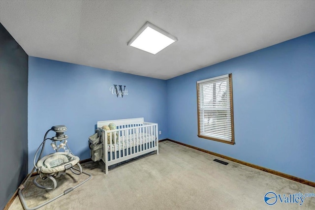 bedroom featuring a nursery area, light colored carpet, and a textured ceiling