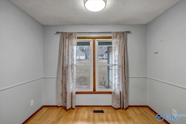 doorway with a healthy amount of sunlight, light hardwood / wood-style floors, and a textured ceiling