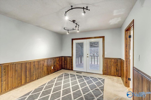 interior space with rail lighting, french doors, and a textured ceiling