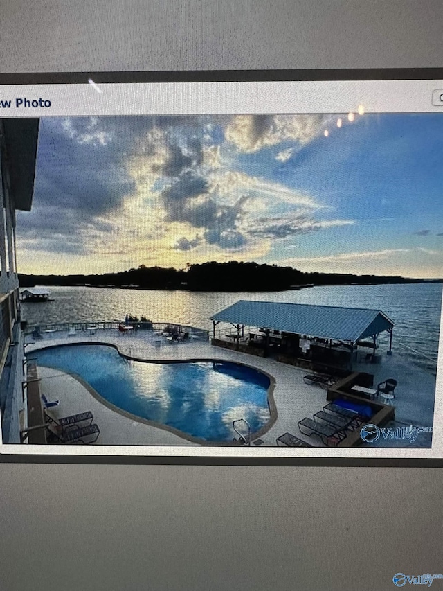 pool at dusk featuring a water view