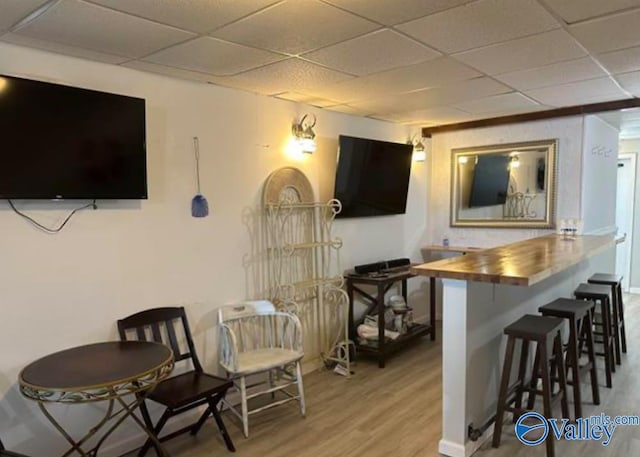 bar featuring butcher block countertops, hardwood / wood-style flooring, and a paneled ceiling