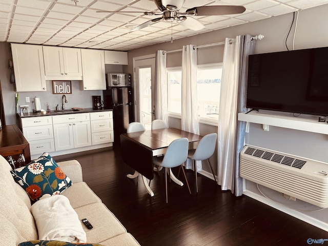 kitchen featuring an AC wall unit, white cabinetry, sink, dark hardwood / wood-style flooring, and ceiling fan