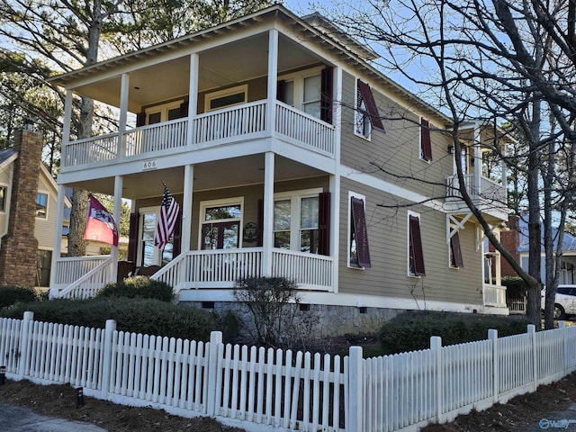 view of front of property with a balcony, fence private yard, a porch, and crawl space