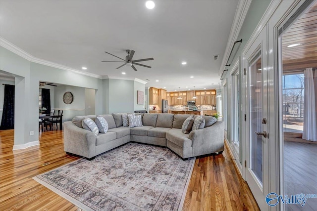 living room with light wood-type flooring, ceiling fan, and ornamental molding