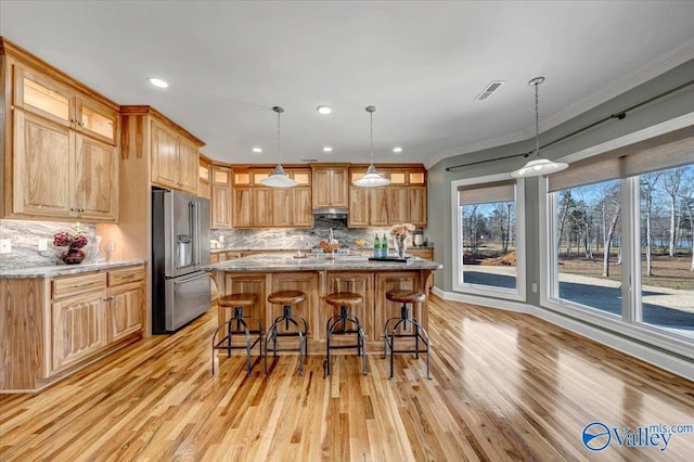 kitchen featuring light stone countertops, pendant lighting, light hardwood / wood-style floors, backsplash, and high end fridge