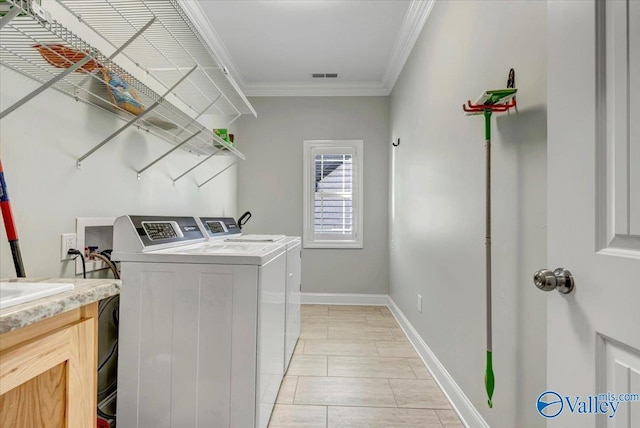 clothes washing area featuring light tile patterned floors, washer and dryer, and ornamental molding