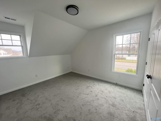 additional living space with carpet, visible vents, vaulted ceiling, and baseboards