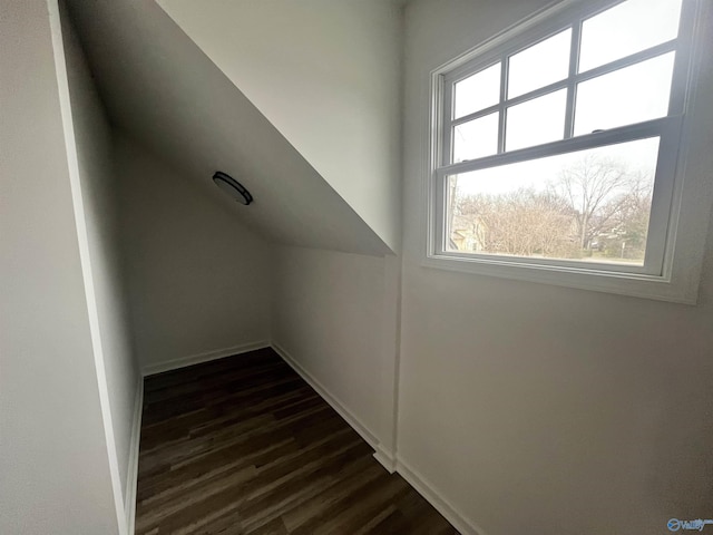 additional living space featuring dark wood-style flooring, vaulted ceiling, and baseboards