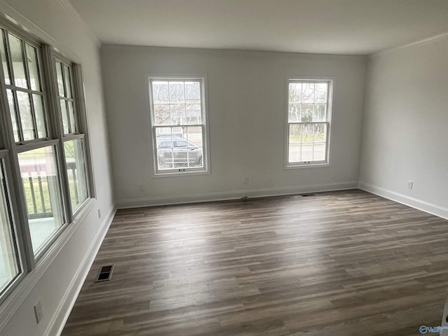 empty room featuring baseboards, visible vents, and dark wood-type flooring