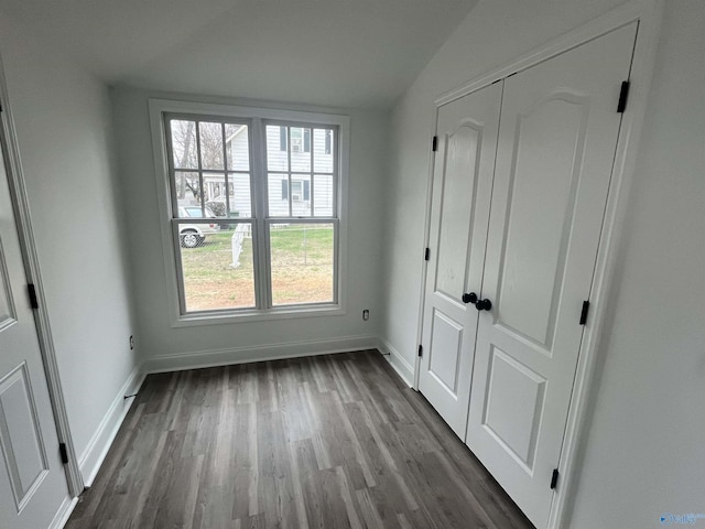 unfurnished bedroom featuring baseboards, dark wood finished floors, and a closet