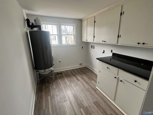 laundry area with washer hookup, light wood finished floors, cabinet space, visible vents, and baseboards