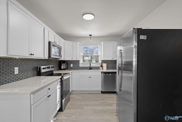 kitchen featuring white cabinetry, sink, backsplash, stainless steel appliances, and light hardwood / wood-style flooring