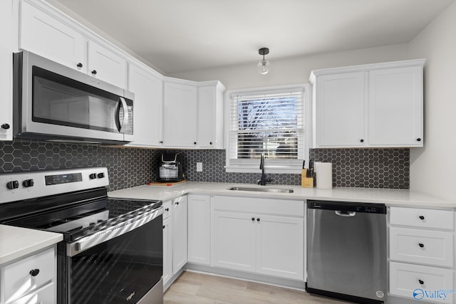 kitchen with tasteful backsplash, appliances with stainless steel finishes, sink, and white cabinets