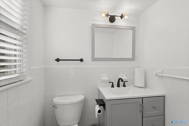 bathroom featuring tile walls, vanity, and toilet