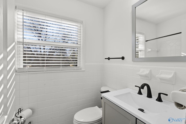 bathroom featuring tile walls, vanity, plenty of natural light, and toilet