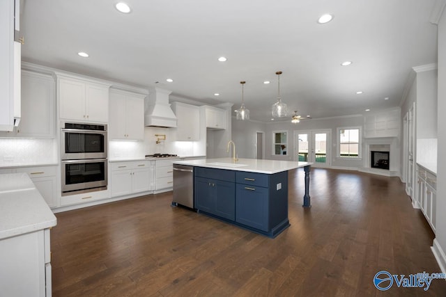 66 Natures Ridge Way, Huntsville, AL 35803 - kitchen with custom range hood, stainless steel appliances, blue cabinets, ornamental molding, and open floor plan