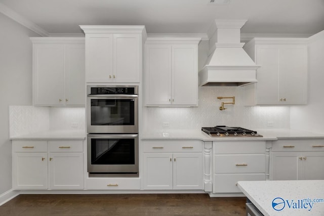 66 Natures Ridge Way, Huntsville, AL 35803 - kitchen with stainless steel appliances, custom exhaust hood, white cabinetry, decorative backsplash, and light stone countertops