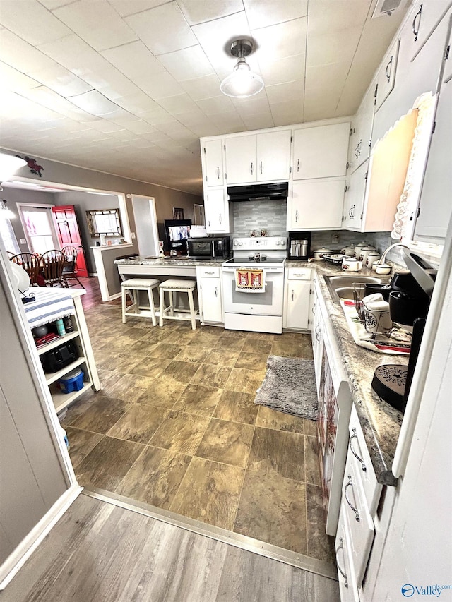 kitchen with white electric range oven, backsplash, white cabinets, and under cabinet range hood