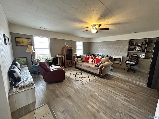 living room with visible vents, ceiling fan, heating unit, and wood finished floors