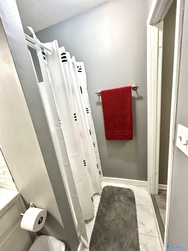 full bathroom with a shower with shower curtain, marble finish floor, and baseboards