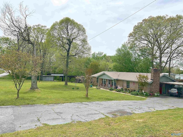 single story home with a front yard, driveway, a carport, and a chimney