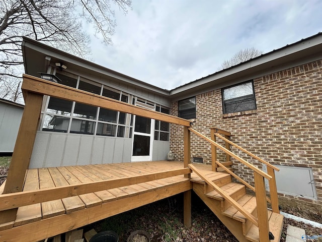 rear view of house featuring a wooden deck and brick siding