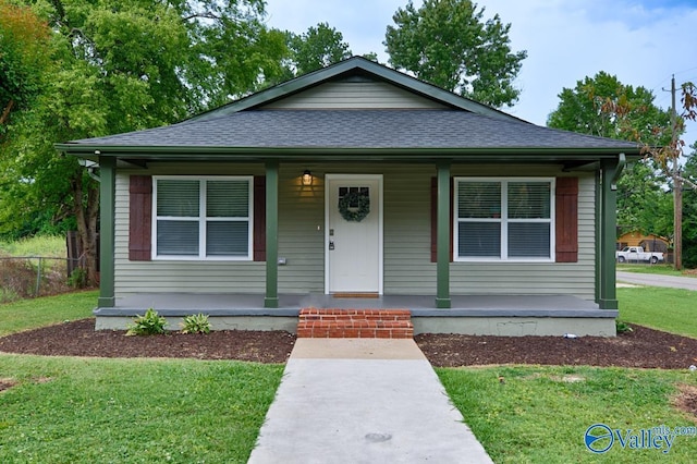 bungalow-style home featuring roof with shingles, a porch, fence, and a front yard