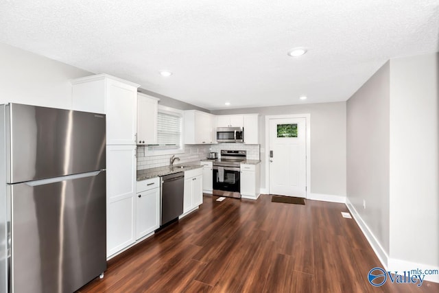 kitchen with white cabinets, dark wood finished floors, light stone counters, stainless steel appliances, and backsplash
