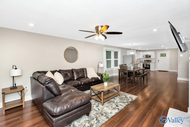 living area featuring ceiling fan, baseboards, and dark wood-type flooring