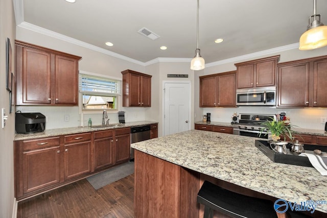 kitchen featuring light stone counters, stainless steel appliances, sink, and hanging light fixtures