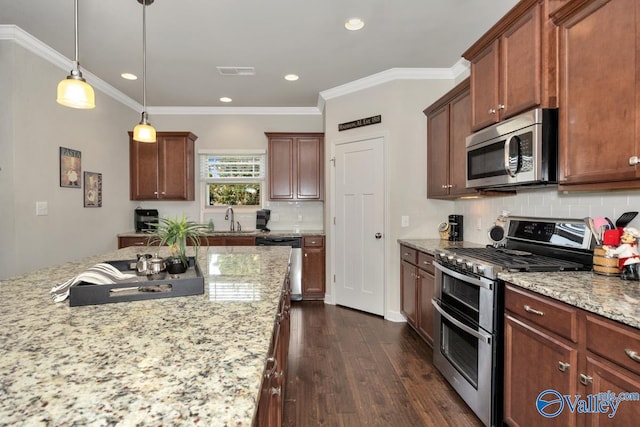 kitchen with pendant lighting, sink, appliances with stainless steel finishes, light stone counters, and tasteful backsplash