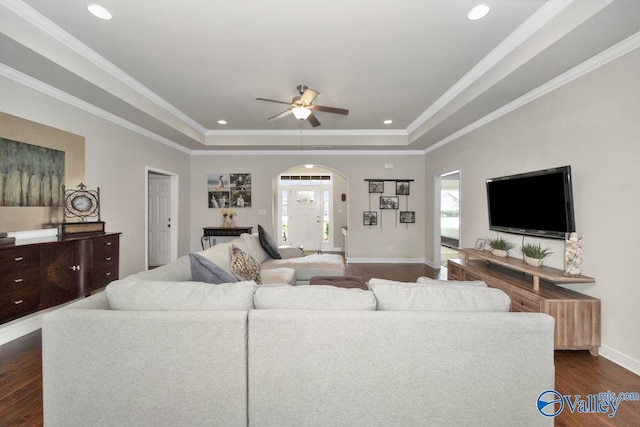 living room with a raised ceiling, ornamental molding, and dark hardwood / wood-style flooring